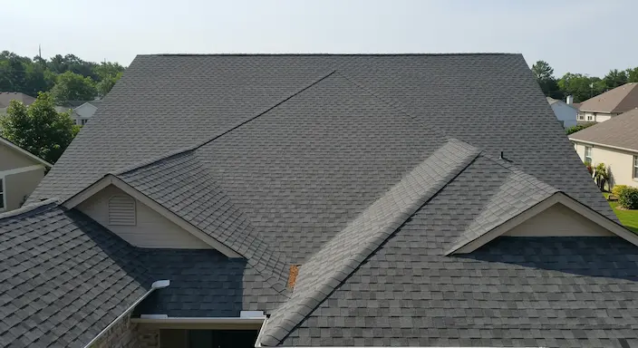residential home with a newly repaired roof under clear skies after storm damage, pristine shingles and clean roof lines